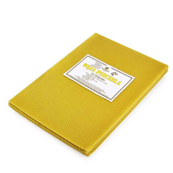 Zdjecie-przedstawia-prostokatna-zolta-weze,-wykonana-z-wosku-pszczelego-w-typie-ula-wielkopolskiego.-Na-wezie-umieszczona-zostala-prostokatna-kartka-z-informacjami-o-sprzedawanej-wezie